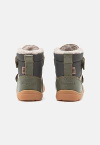 Grüne Stoffstiefel mit einer weichen grauen Fellfütterung, verstellbaren Klettverschlüssen und einer strukturierten Gummisohle, mit dem Logo "bisgaard."