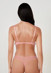 Set di lingerie rosa realizzato in pizzo e raso. Caratterizzato da spalline regolabili, bordi scallop e motivi a pois. Texture trasparente e delicata.