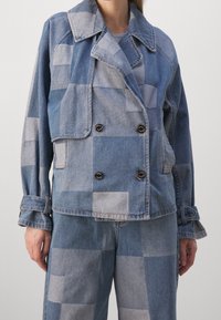 Blue denim jacket featuring a checkered pattern with varying shades, double-breasted design, and two front pockets.