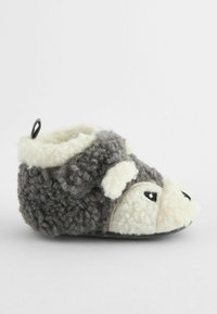 Chausson en peluche gris et blanc en forme de hérisson, avec une texture moelleuse, de grands yeux noirs ronds et une boucle en tissu à l'arrière.