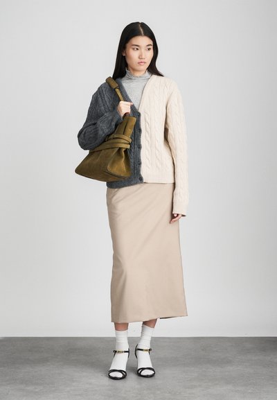 Καλσονα πλεκτή κάρντιγκαν σε γκρι και κρέμα, μίντι φούστα σε μπεζ, λευκές κάλτσες, μαύρες κλειστές γόβες και πράσινη τσάντα. Ομαλές υφές και αντίθετα χρώματα.