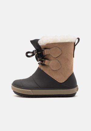 Botte d'hiver pour enfant avec partie inférieure en caoutchouc noir, dessus en daim marron, doublure en polaire blanche et lacets noirs noués en nœud sur le côté.