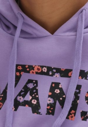 Sweat à capuche lavande avec cordons, arborant des lettres noires audacieuses remplies d'un motif floral rouge, violet et rose sur la poitrine.