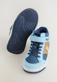 Zapatillas altas azules con parte superior de ante y cuero, que presentan un diseño de dibujos animados en un lado, suela de goma con agarre texturizado y correa ajustable.