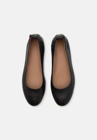 Paire de ballerines en cuir noir avec bouts arrondis et semelles intérieures beiges vues de dessus sur fond blanc.