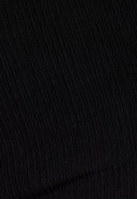 Tessuto nero con una consistenza a coste uniforme, caratterizzato da linee verticali che creano una superficie strutturata e tattile. Adatto per indumenti.