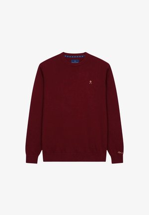 Maronfarbener Strickpullover mit langen Ärmeln, Rundhalsausschnitt, goldenen gestickten Logo auf der Brust und kontrastierendem blauen Detail am inneren Kragen.