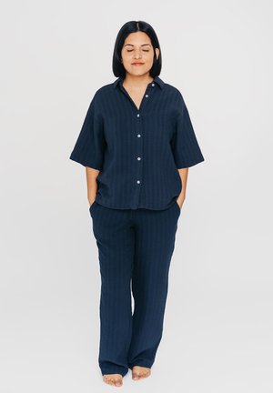 Marineblaue, kurzärmelige Button-Down-Bluse mit vertikalen Streifen, kombiniert mit passenden weiten Hosen. Weicher Stoff, lockere Passform, mit seitlichen Taschen.
