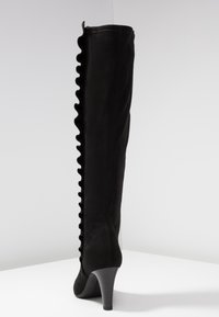Schwarze Wildleder-Stiefel bis zum Knie mit rüschendetail an der Seite und einem eleganten Absatz. Glatte Textur mit einer figurschmeichelnden Silhouette.