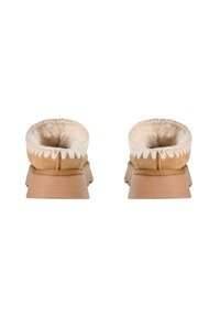 Pantoufles en suede marron avec un intérieur en fausse fourrure. Semelle épaisse, forme arrondie et couture décorative le long du bord supérieur.