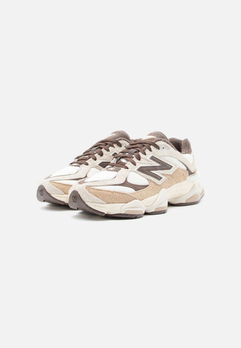 Sneaker beige e marroni in mesh e suede con punta arrotondata, dettagli testurizzati, lacci e suole imbottite. Logo New Balance sul lato.