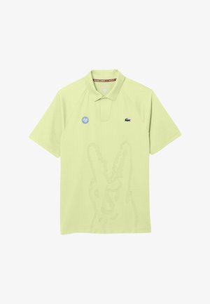 Polo de color verde claro con el logo de Roland Garros en el pecho izquierdo y el pequeño emblema del cocodrilo de Lacoste en el pecho derecho.