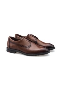 Chaussures habillées en cuir brun avec une forme élégante, une texture lisse et un laçage à cinq œillets. Semelle en caoutchouc noir avec un accent rouge sur le talon.