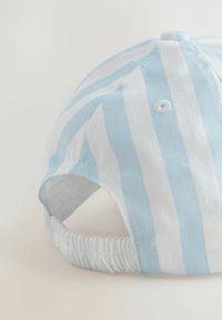 Gorra de rayas azules y blancas hecha de algodón, con un ala curvada y parte trasera elástica para un ajuste ajustable. Detalle de tejido texturizado visible.