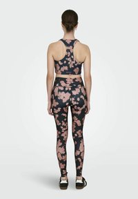 Sport bras i tajice s cvjetnim uzorkom, crne boje s ružičastim cvjetnim motivom. Elastičan, uski dizajn s detaljem na leđima.