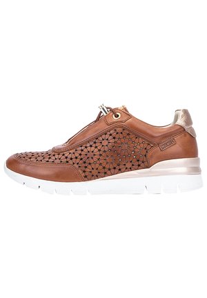 Zapatillas de cuero marrón con un diseño floral cortado a láser, suela media blanca y detalles metálicos. Sistema de cordones con cerradura de cremallera.