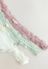 Tre par af blondekantede trusser i lys pink, mintgrøn og hvid, med tekstureret stof og dekorative knapper.