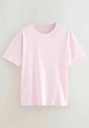 T-shirt di cotone rosa chiaro con maniche corte, scollo rotondo e un piccolo logo ricamato sul lato sinistro del petto. Texture liscia.