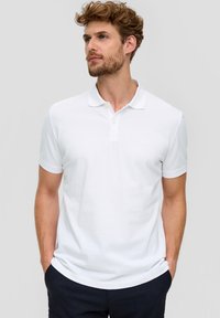 Witte polo shirt gemaakt van gestructureerd katoen, met een drie-knopen sluiting en korte mouwen. Eenvoudig ontwerp, zonder zichtbare patronen of logo's.