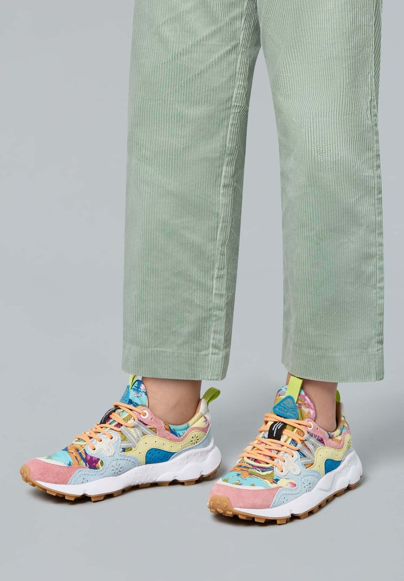 Sneaker colorati in materiali misti, con un design a fantasie che presenta tonalità di rosa, blu e verde, e una suola bianca con scanalature texture.