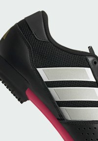 Schwarze Sneaker mit drei reflektierenden silbernen Streifen, pinkfarbener Einlegesohle und strukturiertem schwarzen Mesh-Obermaterial.