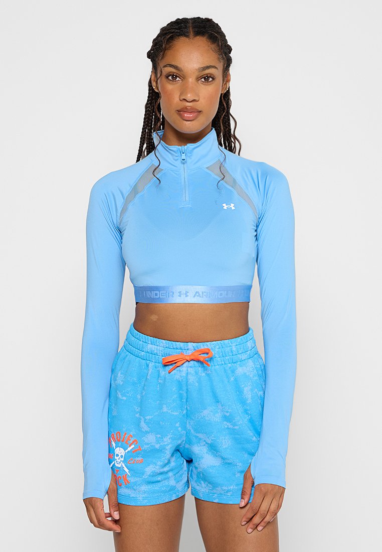 Crop top da allenamento azzurro chiaro con zip e maniche lunghe, caratterizzato da un logo e un design aderente. Abbinato a pantaloni corti blu coordinati con cordino arancione.