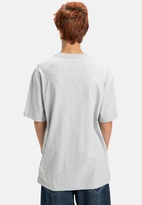 Szara bawełniana koszulka z luźnym krojem, krótkimi rękawami i okrągłym dekoltem, o gładkiej strukturze i prostym wykończeniu dołu.