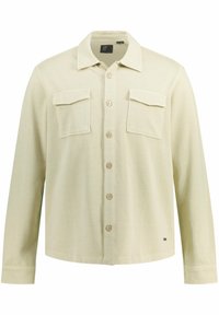 Camisa de botones color beige claro con cuello, dos bolsillos en el pecho y botones de madera. Presenta mangas largas y un dobladillo recto.