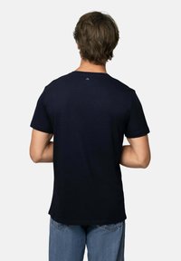 Krótki rękaw, granatowy t-shirt z mieszanki bawełnianej, z okrągłym dekoltem i małym detalem logo na górze pleców, w połączeniu z dżinsami.