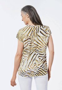 Bluse mit kurzen Ärmeln aus leichtem Stoff, die ein gelb-braunes Zebramuster aufweist, mit drapiertem Rücken und leichten Falten.