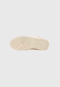 Semelle de sneaker, conçue avec un caoutchouc beige texturé. Présente des motifs de sculpture circulaires et horizontaux pour la traction et la stabilité.