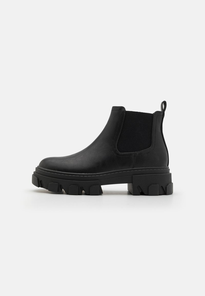 Botas Chelsea de cuero negro con paneles elásticos en los laterales y una suela de goma texturizada con ranuras profundas. Tirador en la parte posterior para facilitar el uso.