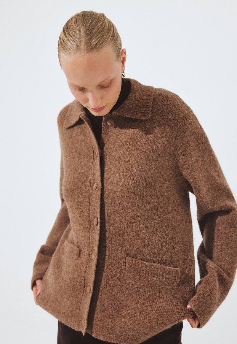 Brown wool blend button-up cardigan with a collar, two front pockets, and a soft, textured finish. Features a relaxed fit and long sleeves.