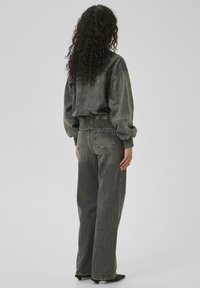 Oversized, dark gray sweatshirt with ribbed cuffs and hem paired with straight-leg, faded gray jeans. Smooth texture and casual fit.