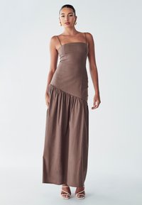 Braunes Maxikleid mit Spaghetti-Trägern, das einen enganliegenden Oberteil und einen gerafften Rock hat. Weiche Textur und diagonale Nahtdetails.