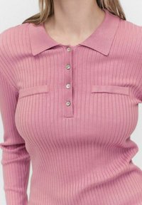 Ribbed pink long-sleeve polo-paita kauluksella, jossa on nappikiinnitys, kaksi rintataskua ja teksturoitu neulepinta.