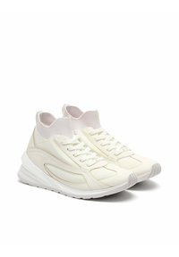 Zapatillas blancas con un cuello de punto en el tobillo, paneles de malla y material sintético texturizado. Presentan cordones planos y una suela acolchada.