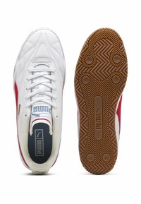 Hvide Puma sneakers har røde accenter, en tekstureret sål med fiskebensmønster og en polstret krave for komfort.