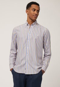 Hemd met lange mouwen met verticale beige en blauwe strepen, knoopsluiting, kraag en een klein logo op de borst. Gladde stoftextuur.