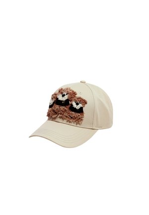 Gorra de béisbol beige con dos pequeñas caras esponjosas de mapache marrón y blanco cosidas en el panel frontal.