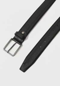 Fekete textúrájú bőr öv ezüst színű, téglalap alakú fémcsattal és több állítható lyukkal, fehér háttérrel.