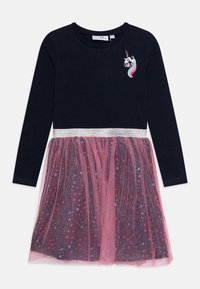 Sukienka z długim rękawem z granatową górą i różow�ą tiulową spódnicą, ozdobiona srebrnym paskiem w talii i kolorowymi wzorami gwiazd. Motyw jednorożca na piersi.