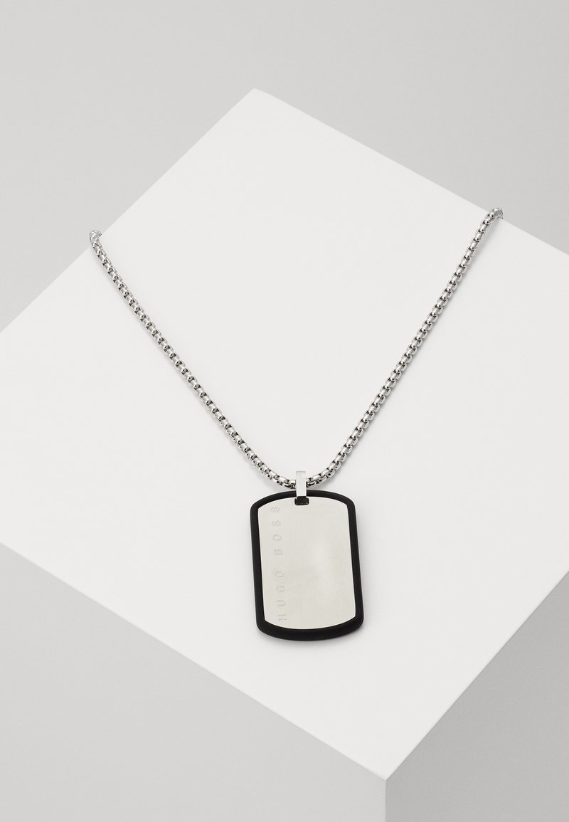 Collier chaîne argenté avec un pendentif plaque militaire rectangulaire souligné de noir, gravé du nom de la marque "HUGO BOSS".