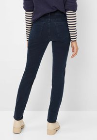 Mørkeblå jeans med slim fit. Har fem lommer og en klassisk talje. Sammen med en stribet langærmet top og lysfarvede sko.