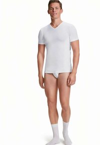 Wit V-hals T-shirt met korte mouwen, gemaakt van gladde stof. Strakke pasvorm met een minimalistisch ontwerp, gecombineerd met lichtgekleurde sokken.