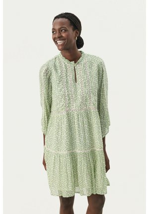 Rochie verde cu model floral, cu mâneci până la trei sferturi, tiv volanat și decolteu în formă de cheie. Fabricată dintr-un material ușor, texturat.