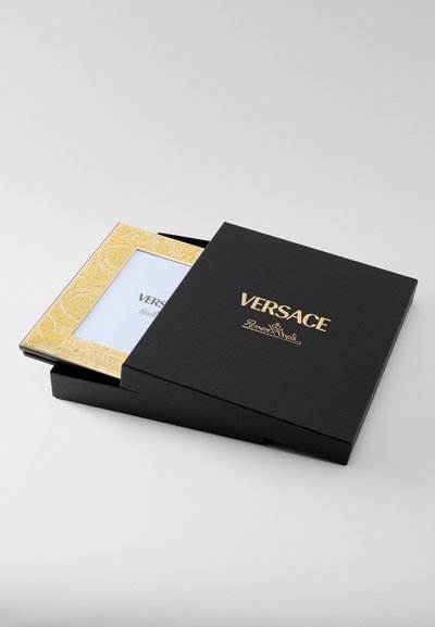 Czarne pudełko Versace ze złotym logo, z ozdobną złotą ramką wewnątrz do wystawiania zdjęć, gładka powierzchnia, kompaktowy, kwadratowy kształt.