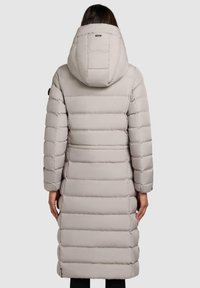 Pufferjakke i lys beige med hætte, lang længde, vandret quiltet design og elastiske mansjetter. Glat tekstur med sidelommer.