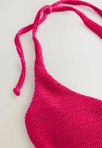 Svijetlo ružičasti bikinijski top s teksturiranom tkaninom i uvrnutim trakama, s valovitim uzorkom i čvorom na vratu.