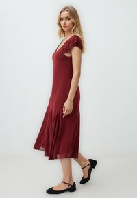 Bordeaux midi-jurk met kapmouwen, aansluitend lijfje en uitlopende rok. Gemaakt van soepel stof met subtiele drapering aan de zoom.